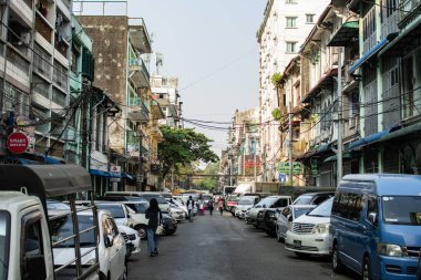 Yangon, Myanmar - 30 Aralık 2019: Central City 'de park halindeki arabaların ve yayaların yürüdüğü dar bir sokakta günlük hayat yaşanıyor