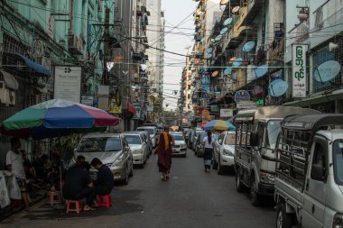 Yangon, Myanmar - 30 Aralık 2019: Central City 'de bir keşiş dar bir sokakta araba trafiğine karşı yürüyor