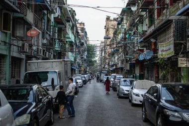 Yangon, Myanmar - 30 Aralık 2019: Central City 'de park halindeki arabaların ve yayaların yürüdüğü dar bir sokakta günlük hayat yaşanıyor