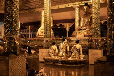 Yangon, Myanmar - 30 Aralık 2019 Shwedagon Pagoda 'da sütunları olan sarı yansıtma odasındaki altın Buda heykelleri