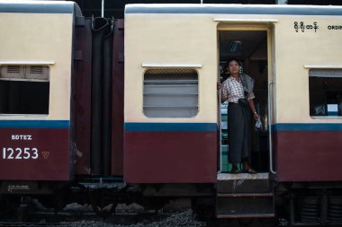 Yangon, Myanmar - 31 Aralık 2019: Yangon tren istasyonunda geleneksel dairesel trenin sıradan sınıfının kapısında duran burmalı bir adam