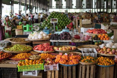 YANGON, MYANMAR - 31 Aralık 2019: Arka planda günlük ziyaretçilerin bulunduğu yerel bir pazarda taze meyve ve sebzeler sergileniyor