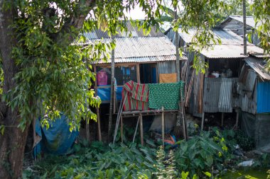 Yangon, Myanmar 'ın dışındaki bir nehrin üzerinde birkaç tahta direğin üzerinde duran demirden yapılmış basit bir ev.