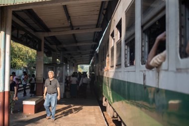 YANGON, MYANMAR - 31 ARALIK 2019: Geleneksel çember tren yolculuğu sırasında bir platform durağındaki yerel Burmalı insanlara bakın