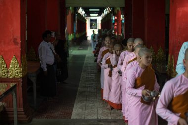 YANGON, MYANMAR - 12020 OCAK: Pembe cüppeli genç rahipler sabah yemeklerini Swe Taw Myat Pagoda yakınlarındaki kaselerinde yemek için sıraya giriyorlar