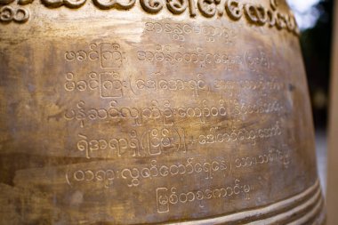 BAGAN, NYAUNG-U, MYANMAR - 2 HAZİRAN 2020: Tarihi bir pagoda tapınağının yanındaki büyük bir Budist çanı üzerindeki Birmanya metninin kapatılması