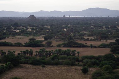 BAGAN, NYAUNG-U, MYANMAR - 3 HAZİRAN 2020: Bagan 'ın uçsuz bucaksız ovalarına tarihi tapınakları ve tarlalarıyla uzun Nan Myint kulesinden bakıyor