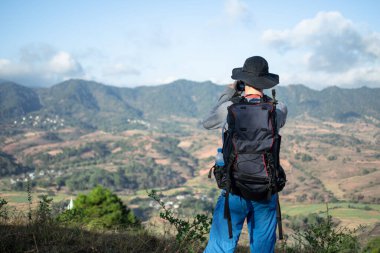Kalaw 'dan Inle Gölü' ne, Shan State, Myanmar 'a yürürken yuvarlanan tepelerin ve çiftlik arazilerinin fotoğrafını çeken bir turist.