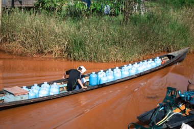 Shan State, Myanmar - 7 Ocak 2020: Geleneksel tekne Inle Gölü yakınlarındaki çamurlu bir kanaldan birçok mavi su şişesi taşıyor, Nyaung Shwe