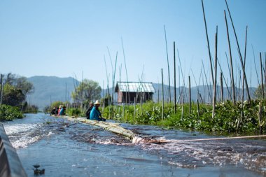 Shan State, Myanmar - 7 Ocak 2020: Yerel halk bambu üzerinde oturuyor ve Inle Gölü, Nyaung Shwe 'de bir teknenin sürüklediği bir nehirde yüzüyor.