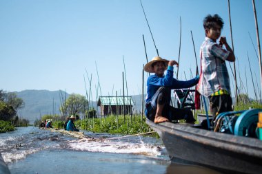 Shan State, Myanmar - 7 Ocak 2020: Yerel halk bambu üzerinde oturuyor ve Inle Gölü, Nyaung Shwe 'de bir teknenin sürüklediği bir nehirde yüzüyor.