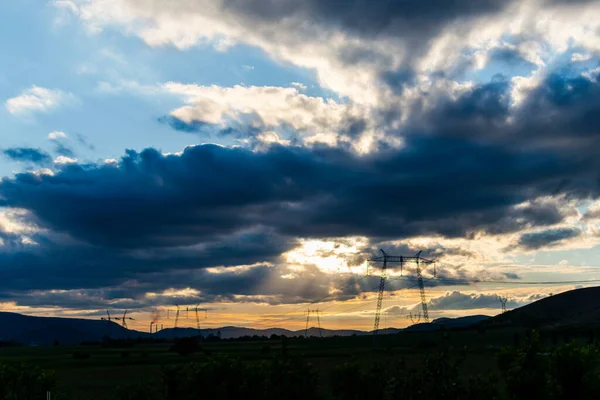 sunset sky with clouds over field with electric towers
