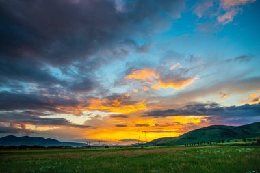 Gün batımı gökyüzü dağların üzerinde manzara ve çim çayırları 