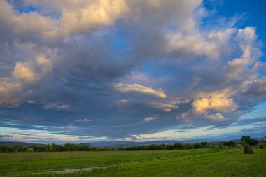 Dağların kırsal arazisi ve yeşil çimenler, günbatımı gökyüzü