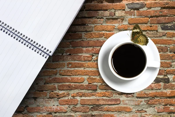 コーヒーのカップと赤レンガの背景に蝶 — ストック写真