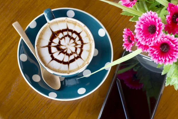 Koffiebeker en smartphone op een houten tafel — Stockfoto