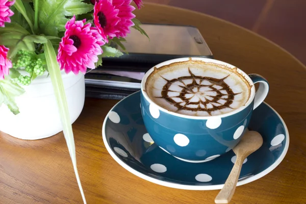 Koffiebeker en smartphone op een houten tafel — Stockfoto