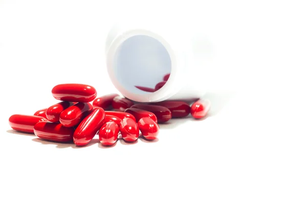 Píldoras rojas y frasco de pastillas en blanco —  Fotos de Stock