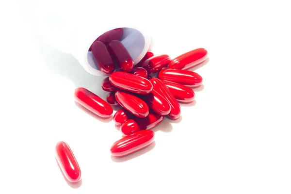 Píldoras rojas y frasco de pastillas en blanco —  Fotos de Stock