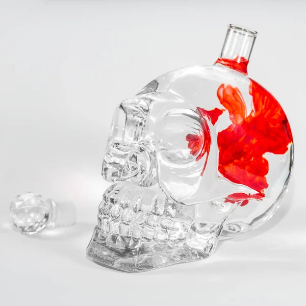 Glass skull with red and orange ink drops in water, alcohol