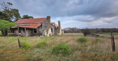 Issız, yıpranmış bir çiftlik evi bulutlu gökyüzünün altında geniş bir kırsal alanda bulunur. Uzun otlar, ahşap bir çit ve çıplak ağaçlar nostaljiyi ve unutulmuş kırsal yaşamı çağrıştırıyor. Victoria Avustralya