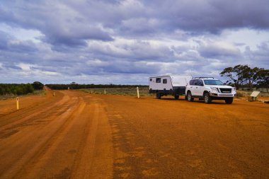 Uzak bir çölde geniş kırmızı toprak bir yol. Sahne, bulutlarla dolu dramatik bir gökyüzü altında seyahat, macera ve açık hava kampı çağrıştırıyor. Batı Avustralya 'daki Johnston Gölü' ne gidiyoruz. Gri göçebeler seyahat eder