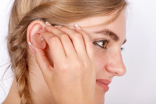 Mujer insertando un audífono en el oído — Foto de Stock