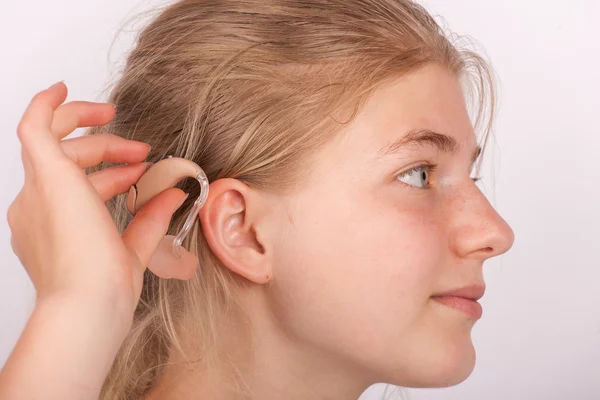 Girl insertin hearing aid into ear — Stock Photo, Image