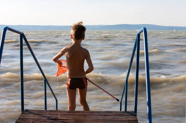 Niño con red de aterrizaje en la playa — Foto de Stock