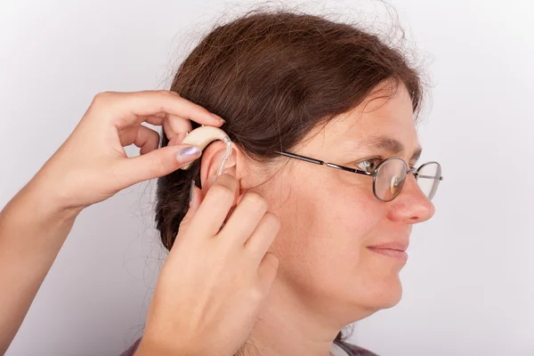 Mujer encajando con un audífono — Foto de Stock