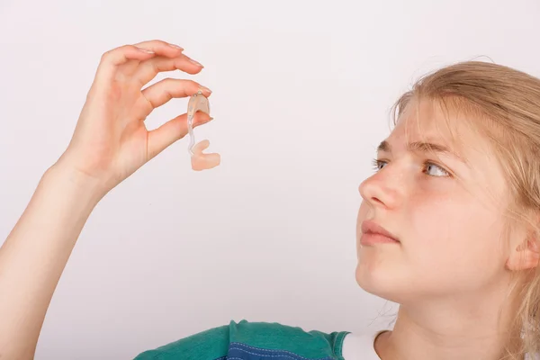 Chica inspeccionando un audífono — Foto de Stock