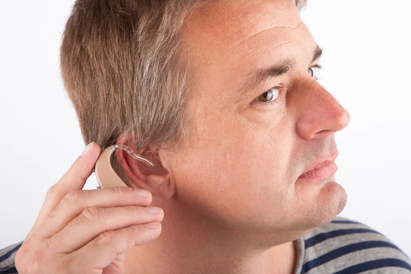 Senior man inserting a hearing aid — Stock Photo, Image
