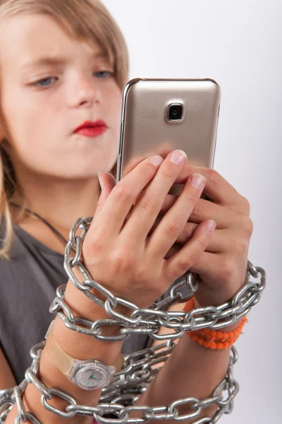 Young girl shackled with a chain using smartphone — Stock Photo, Image