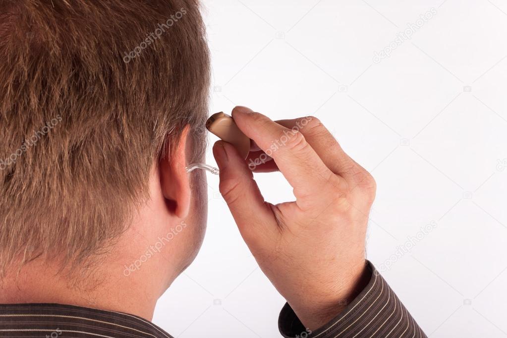 Close up ear of a man inserting a hearing aid