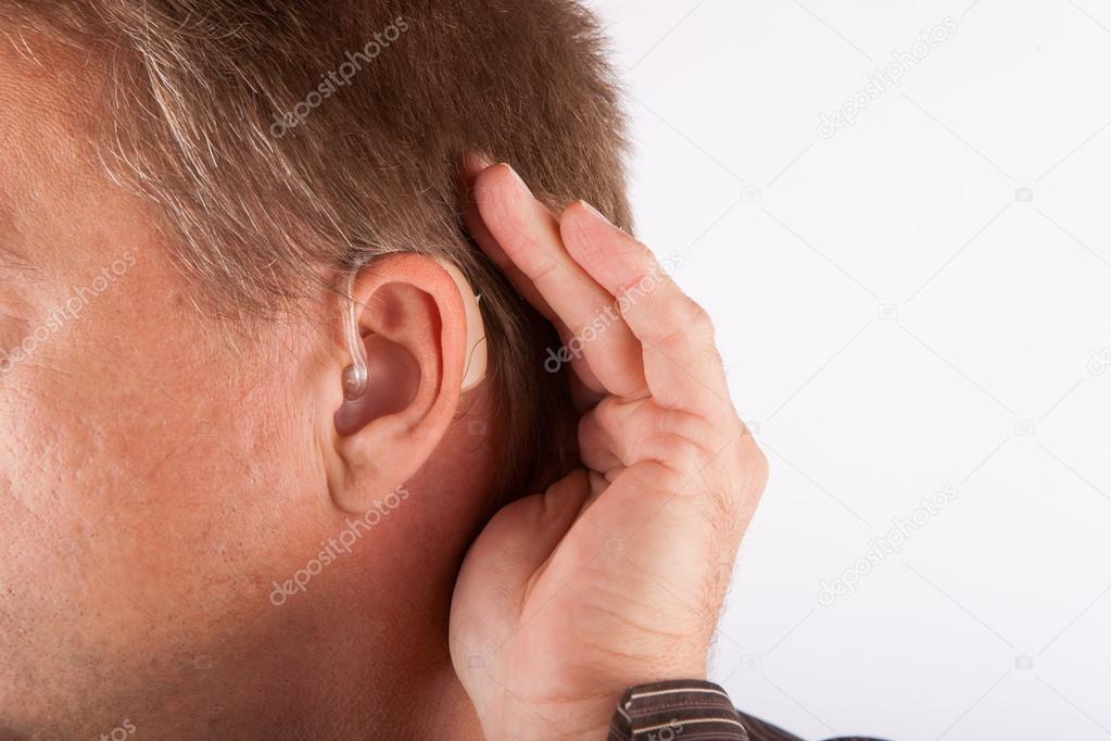 Close up ear of a man wearing hearing aid and listening for a qu