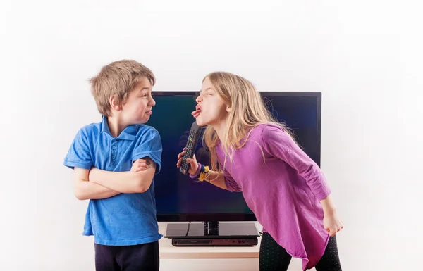 Frères et sœurs qui se disputent au sujet de la télécommande — Photo