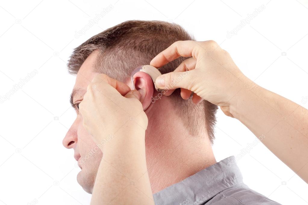 Hands inserting hearing aid