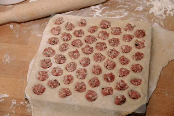 Frau formt selbst gemachte Knödel mit Ohren in der Küche. Knödel in Nahaufnahme modellieren. Weibliche Hände formen Knödel. — Stockfoto