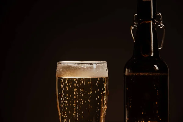 Makro bira şişesi ve arka planda bir bardak bira.