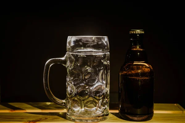 Makro bira şişesi ve arka planda bir bardak bira.