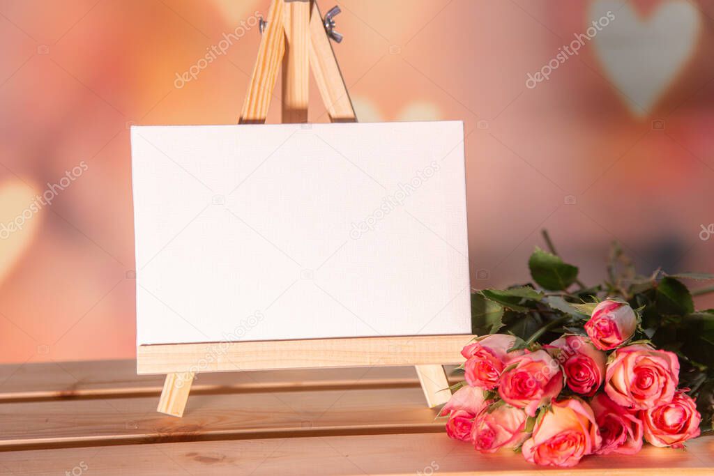 Pink roses on a wooden background, white place for text, easel, pink background for the holiday of February 14 or March 8, Valentines Day