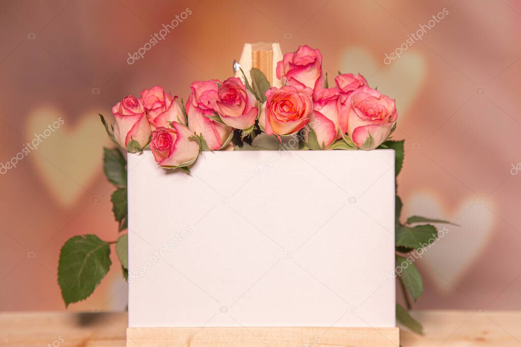 Pink roses on a wooden background, white place for text, easel, pink background for the holiday of February 14 or March 8, Valentines Day