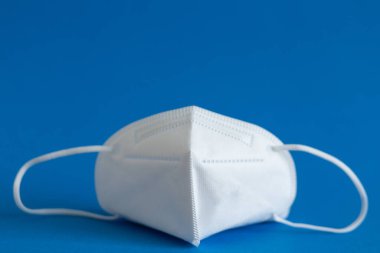 FFP3 maskesi, burun damlası, termometre, tabletler, çeşitli ilaçlar masanın üzerinde duruyor, üst görünüm, mavi arkaplan, düz yüz.