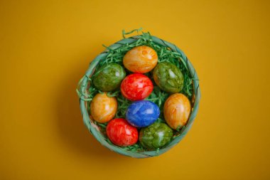 Paskalya kartı. Düz kompozisyon, sarı arka planda bir sepette paskalya yumurtaları. Üst görünüm