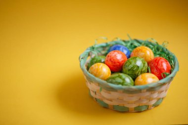 Paskalya kartı. Düz kompozisyon, sarı arka planda bir sepette paskalya yumurtaları. Üst görünüm