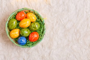 Paskalya kartı. Beyaz arka planda bir sepette paskalya yumurtalarının olduğu düz bir kompozisyon. Üst görünüm