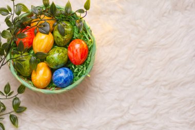 Paskalya kartı. Beyaz arka planda bir sepette paskalya yumurtalarının olduğu düz bir kompozisyon. Üst görünüm