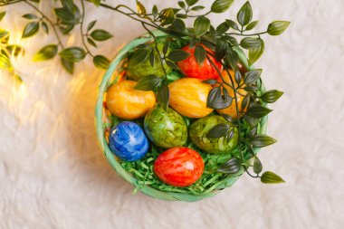 Paskalya kartı. Beyaz arka planda bir sepette paskalya yumurtalarının olduğu düz bir kompozisyon. Üst görünüm