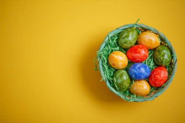 Paskalya kartı. Düz kompozisyon, sarı arka planda bir sepette paskalya yumurtaları. Üst görünüm