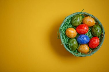 Paskalya kartı. Düz kompozisyon, sarı arka planda bir sepette paskalya yumurtaları. Üst görünüm